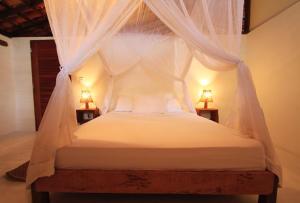 ein Schlafzimmer mit einem Himmelbett mit zwei Lampen in der Unterkunft Alto Bonito - Atins in Atins