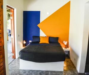 1 dormitorio con 1 cama con pared naranja y azul en Nomadas 5 bdrs villa with private pool 2nd line to beach, en Las Terrenas