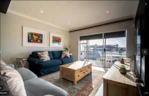 a living room with a blue couch and a table at Ships Bell at Port St Francis in St Francis Bay