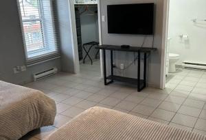 1 dormitorio con TV y suelo de baldosa en Hôtel Ardouin, en Nominingue 10 fotos más