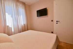 a bedroom with a bed and a television on the wall at Noir Design Wohnung in Trogir