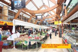 un marché de producteurs avec des gens qui se promènent dans un bâtiment dans l'établissement Calm and central apartment, à Quimper