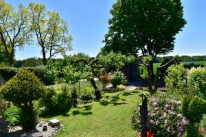 Un jardín con flores y árboles en un día soleado. en La Datcha, en Unterschleißheim