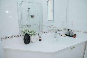 a white bathroom with a sink and a mirror at Villa Aphrodite in Paradise Gardens - 3bd with Private Pool by VICHY Holidays in Nea Paphos