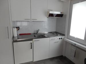 eine kleine Küche mit weißen Schränken und einer Spüle in der Unterkunft Ferienwohnung Falknis in Maienfeld mit Blick auf die Berge - b48844 in Maienfeld