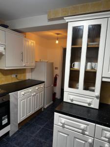 Una cocina con gabinetes blancos y un refrigerador. en Apex house Rainham, en Dagenham Dock 6 fotos más
