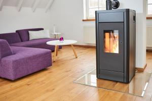 d'un salon avec une cheminée et un canapé violet. dans l'établissement Komfortables Ferienhaus In Purer Natur, à Edertal