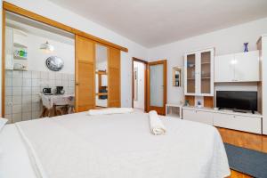 a bedroom with a large white bed and a kitchen at Apartments Marija in Senj