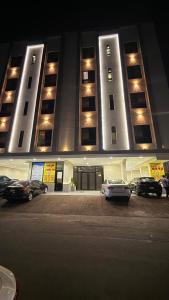 un grande edificio con auto parcheggiate in un parcheggio di شقة الفيصلية a Gedda