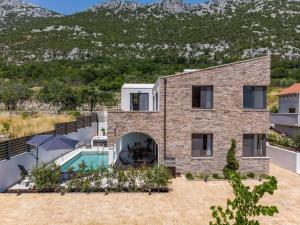 a brick house with a pool and mountains in the background at Villa Eden with heated pool in Omiš