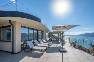 a row of chairs and an umbrella on a balcony at Alleinstehende Villa Mit Pool Und Traumaussicht in Castelletto di Brenzone