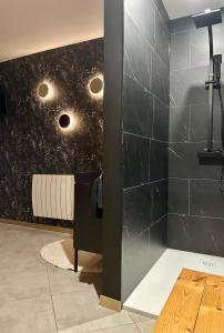 LandreciesLa cachette de Georgette的浴室的墙壁贴着黑色瓷砖，上面装有灯。