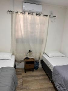 Cette chambre comprend 2 lits jumeaux et une fenêtre. dans l'établissement Andradas House - Casa em Uruguaiana, à Uruguaiana