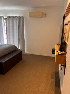 - une chambre avec un lit et une télévision dans l'établissement Andradas House - Casa em Uruguaiana, à Uruguaiana