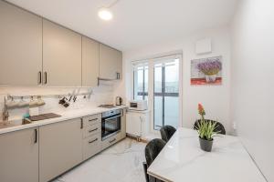 a kitchen with white cabinets and a table with chairs at Cozy airport apartment in Karmelava