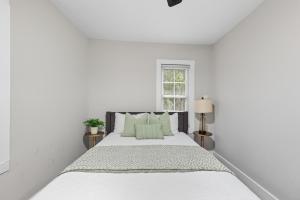 a white bedroom with a large bed with green pillows at Little Indale Haus - Near Downtown and Prince Ave in Athens