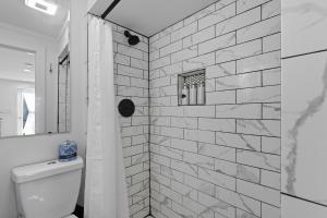 a white tiled bathroom with a toilet and a shower at The Briarcliff Suite in Athens