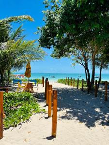 ein Sandstrand mit Tisch und Stühlen und dem Meer in der Unterkunft Fonte dos Corais - Suíte Lua na Praia in Maragogi