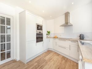 a white kitchen with white cabinets and wooden floors at Dove Cottage in Inverness +18 photos