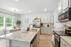 eine Küche mit weißen Schränken und Granitarbeitsflächen in der Unterkunft New Listing The Neutral Nook with Firepit in Athens