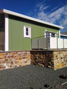 une maison verte avec un mur en pierre dans l'établissement Ferienhaus Mit Grill In Bad Marienberg, à Bad Marienberg