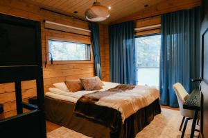 ein Schlafzimmer mit einem Bett in einem Zimmer mit Fenstern in der Unterkunft Aurora B Luxury Lodge in Kuusamo + 90 Fotos