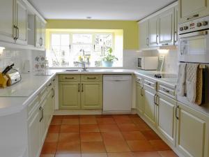 a kitchen with white and green cabinets and a window at East House Farm in Beckermonds