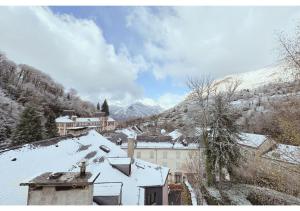 a town covered in snow with mountains in the background at Bel appartement 4 à 6 personnes, ambiance chalet in Eaux-Bonnes