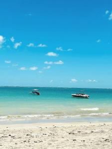 two boats in the water on a beach at Fonte dos Corais - Suíte Lua na Praia in Maragogi