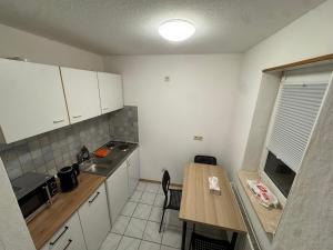 a kitchen with white cabinets and a wooden table at City Apart am MUSEUM nahe BADEWELT in Sinsheim