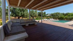 un patio cubierto con sofá y piscina en BALiPALAZEVILLA, en Tanah Lot