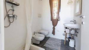 Un baño blanco con inodoro y lavabo. en BALiPALAZEVILLA, en Tanah Lot