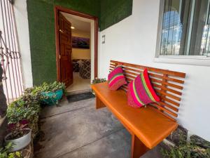 Cusco Imperium House في San Antonio: مقعد خشبي مع وسادتين ملونتين عليه