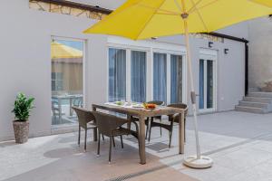 einen Tisch und Stühle mit gelbem Regenschirm auf einer Terrasse in der Unterkunft Ferienhaus in Rabac mit beheizbarem Privatpool für 5 Personen in Rabac