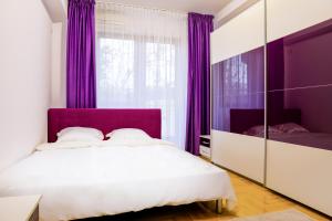 1 dormitorio con cortinas moradas y 1 cama blanca en Elegant Central Stay - Targul de Craciun Craiova, en Craiova
