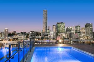a swimming pool on the roof of a building with a city skyline at Spice Apartments by CLLIX in Brisbane