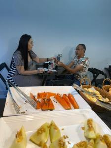deux personnes assises à une table avec une assiette de nourriture dans l'établissement Pousada Maranata, à Aparecida 8 autres photos