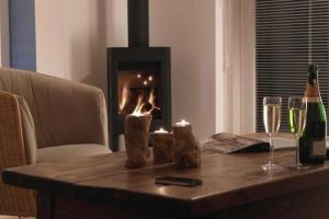 einem Holztisch mit Weingläsern und einem Kamin in der Unterkunft Luxus-Villa, zu Fuß zum Strand, Dünenansicht mit privatem Whirlpool in Julianadorp