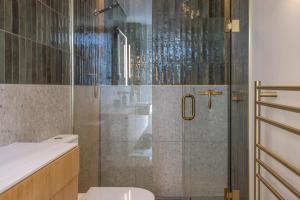 a bathroom with a shower with a toilet and a sink at Birdsong Sanctuary - Be My Guest Waiheke in Waiheke Island +33 photos