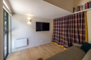 a living room with a couch and a tv at Birdsong Sanctuary - Be My Guest Waiheke in Waiheke Island