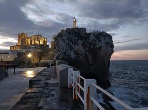 un faro in cima a una roccia con l'oceano di Villa La Perla De Sonabia a Oriñón