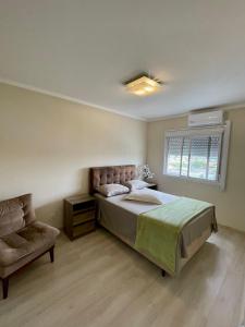 ein Schlafzimmer mit einem Bett und einem Stuhl und einem Fenster in der Unterkunft Apartamento Cond JK Parque Club in Pelotas + 5 Fotos