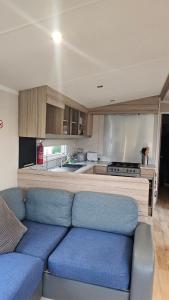 a living room with a blue couch in a kitchen at Sunrise Holidays Skegness - Pearl in Skegness
