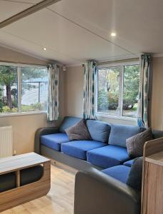 a living room with a blue couch in a caravan at Sunrise Holidays Skegness - Pearl in Skegness