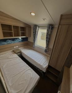 a small room with two beds and a window at Sunrise Holidays Skegness - Pearl in Skegness +6 photos