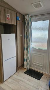a kitchen with a refrigerator and a window at Sunrise Holidays Skegness - Pearl in Skegness