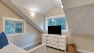 ein Schlafzimmer mit einem Bett und einem Fernseher auf einer Kommode in der Unterkunft Cozy Cannon Beach Home Near Haystack Rock Downtown Steps from the Sea by AvantStay in Cannon Beach