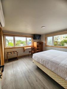 ein Schlafzimmer mit einem Bett, einem Schreibtisch und Fenstern in der Unterkunft suites puerto varas camino al corazon in Puerto Varas