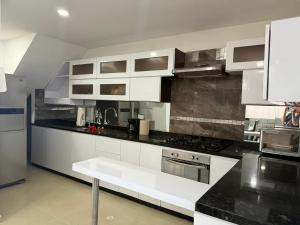 une cuisine avec des armoires blanches et un comptoir noir dans l'établissement Bonito apto en el corazon de Yopal, à Bogotá