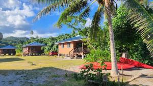 a resort with a palm tree and a house at HUAHINE- Fare Montagne in Parea